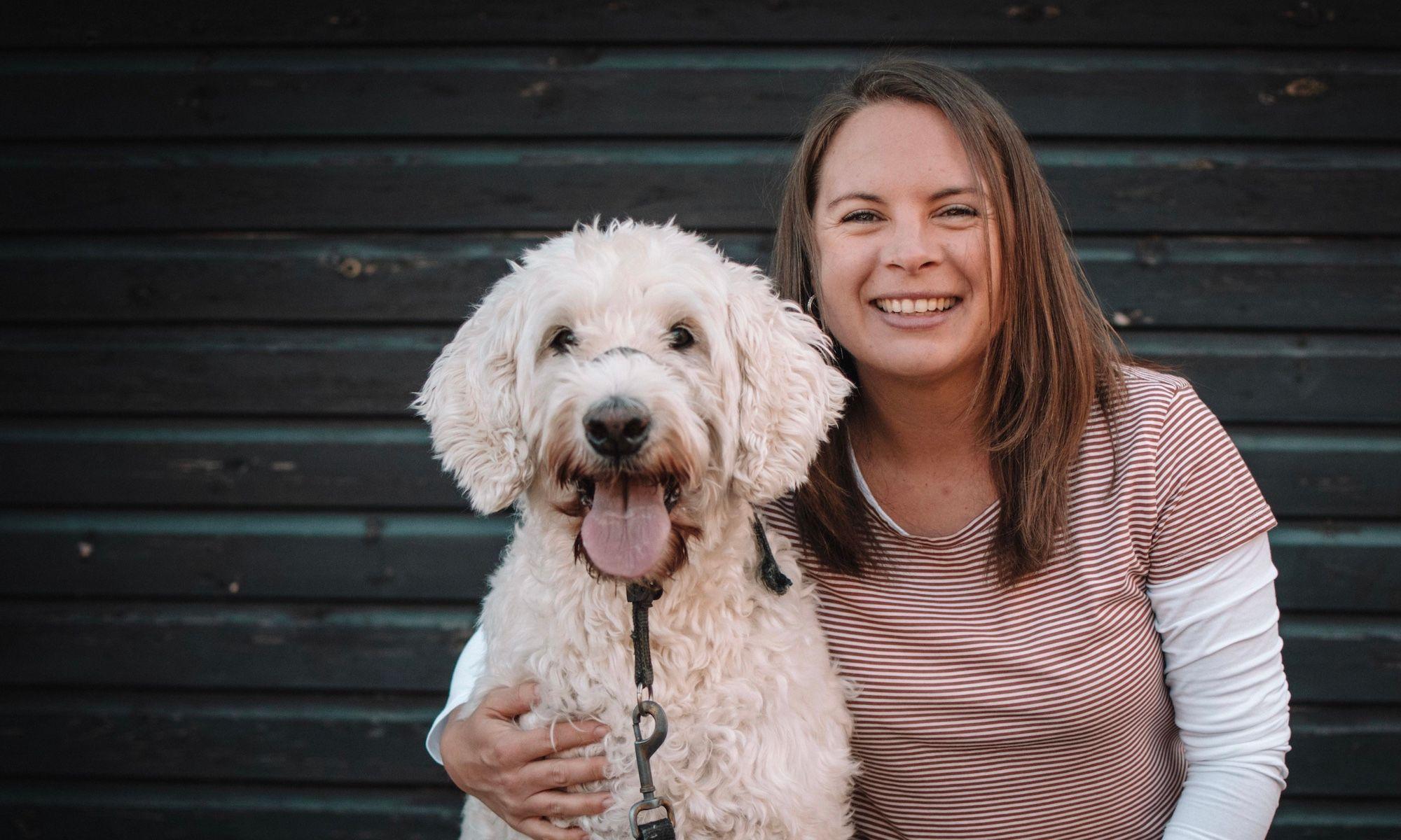 Freestyle Office Manager Claire de Scarfo smiling and cuddling her big white fluffy dog Tess.
