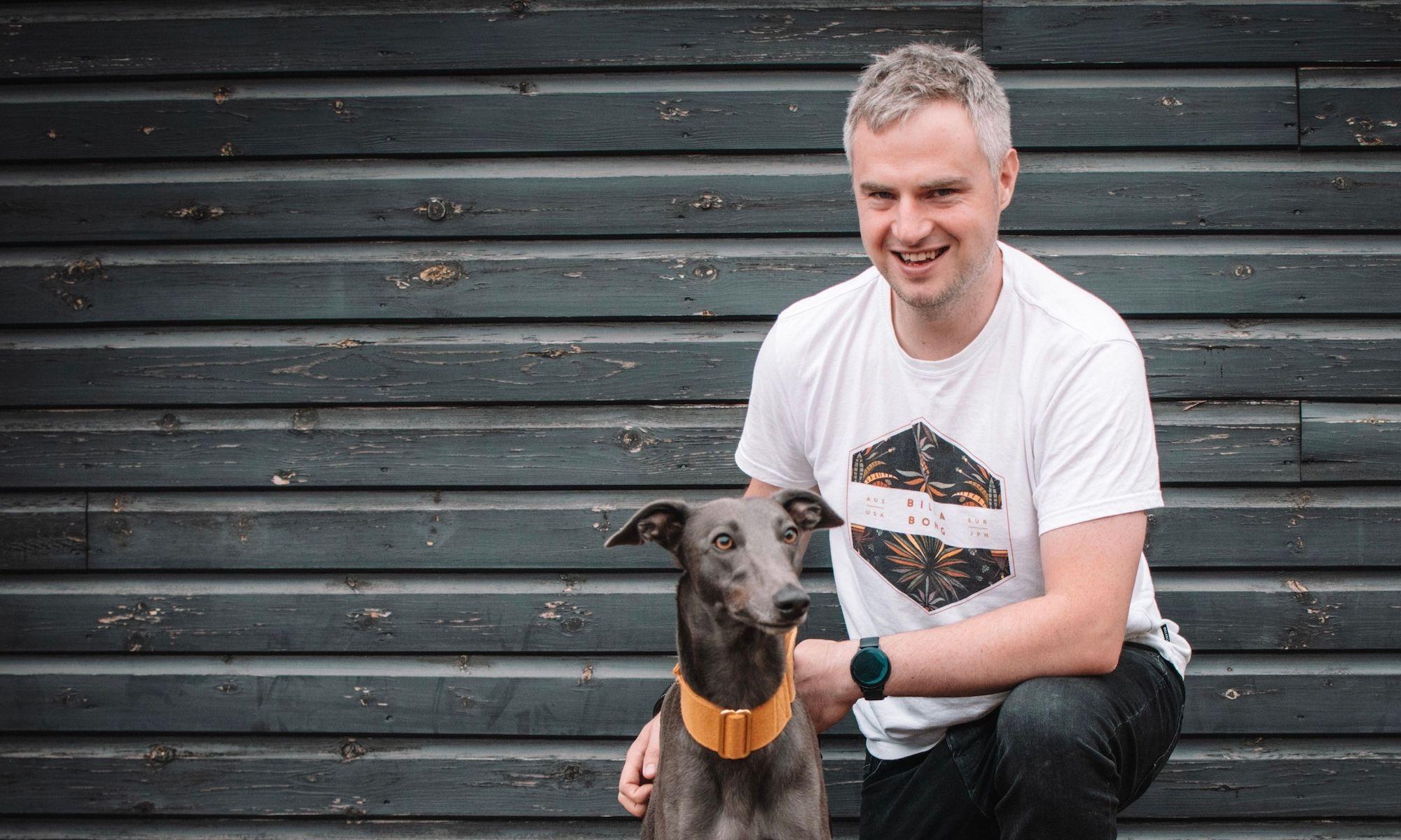 Freestyle Full stack developer Mat Hope smiling and cuddling his greyhound dog Rodney.