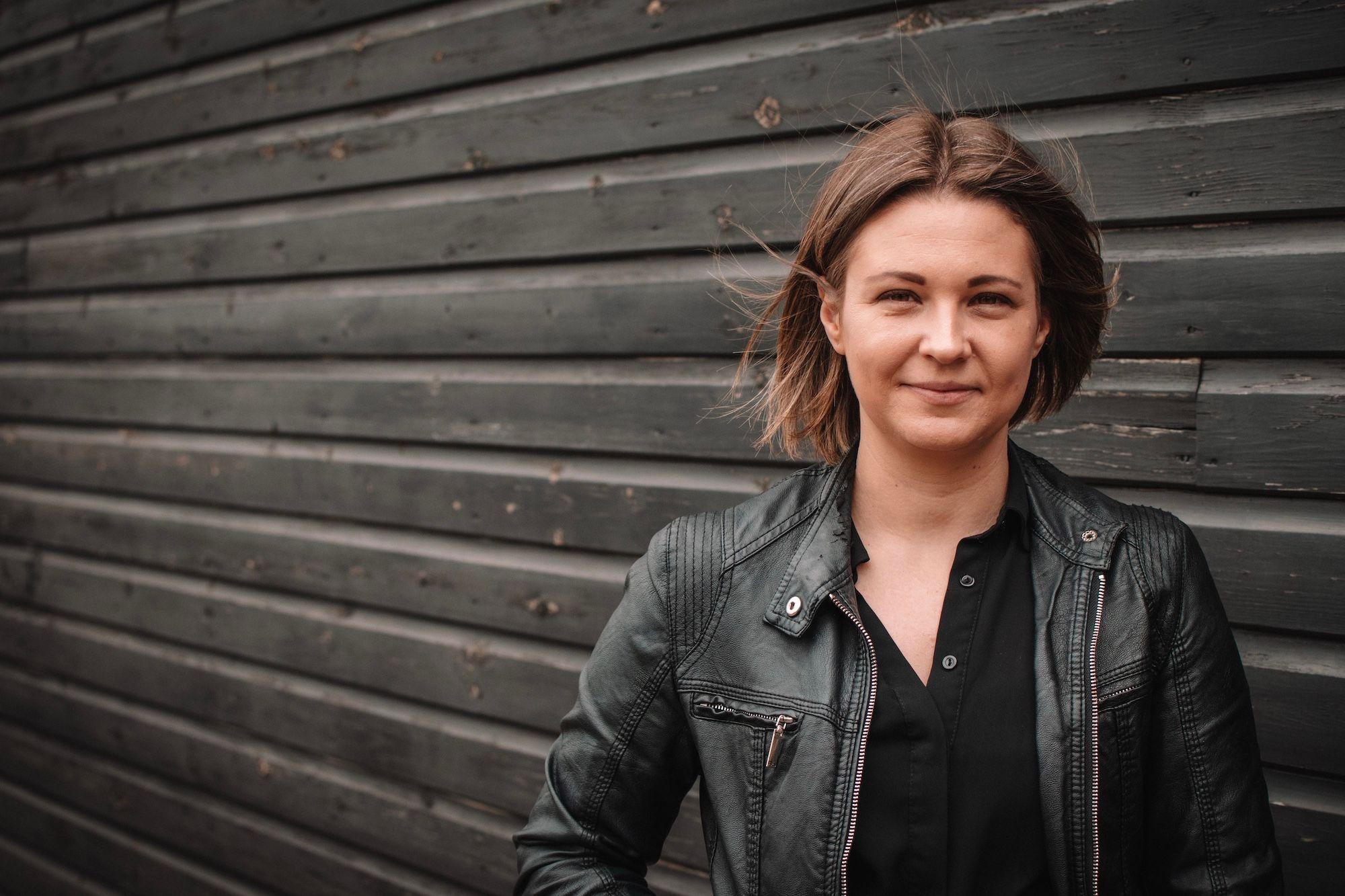 Freestyle Managing Director Emma Simkiss smiling in front of a black wooden wall.